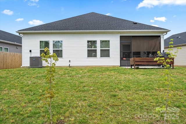 rear view of house featuring central AC, fence, a sunroom, and a lawn