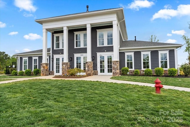 greek revival inspired property with french doors, stone siding, and a front yard