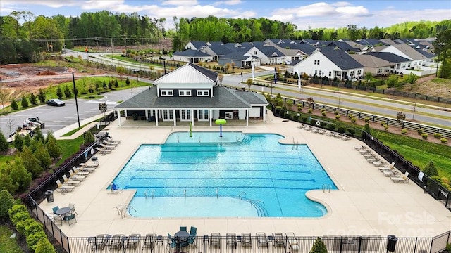 community pool with fence, a residential view, and a patio