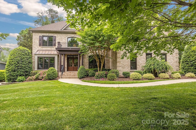 french country style house featuring french doors, a balcony, a front lawn, and brick siding