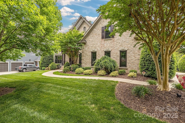 view of front of house featuring brick siding, driveway, a front yard, and a garage