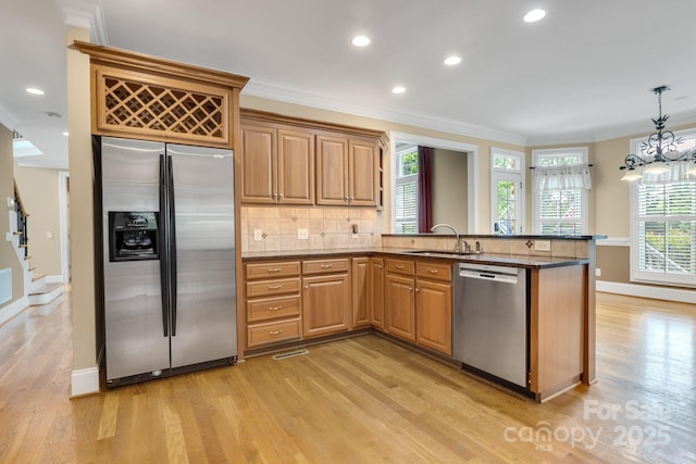 kitchen featuring crown molding, stainless steel appliances, and light wood-style flooring