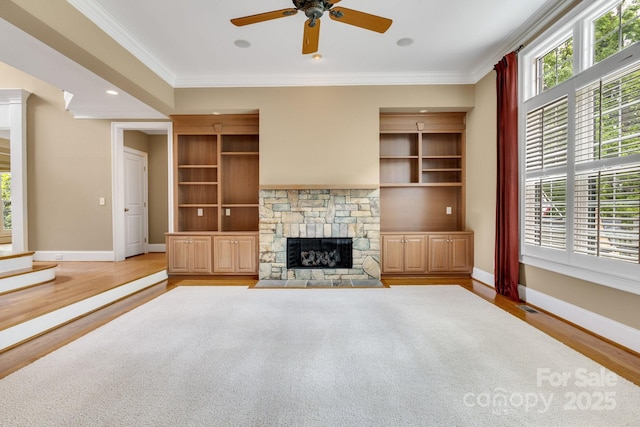 unfurnished living room with a healthy amount of sunlight, baseboards, crown molding, and wood finished floors