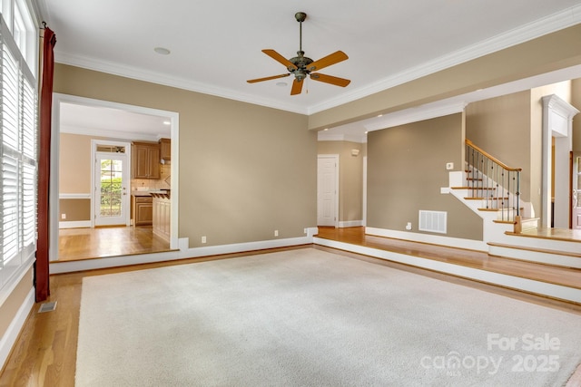 unfurnished living room featuring visible vents, ornamental molding, baseboards, ceiling fan, and light wood-style flooring