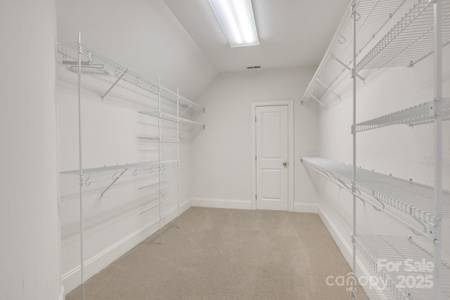 spacious closet featuring visible vents, carpet flooring, and vaulted ceiling