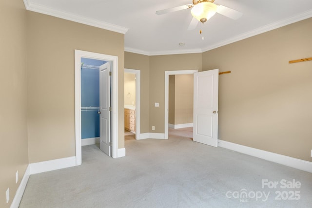 unfurnished bedroom featuring crown molding, light colored carpet, baseboards, a spacious closet, and a closet