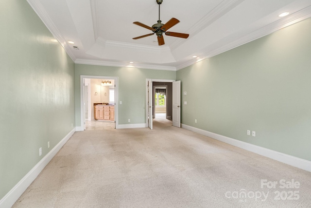 unfurnished bedroom with a tray ceiling, ensuite bath, ornamental molding, and light carpet