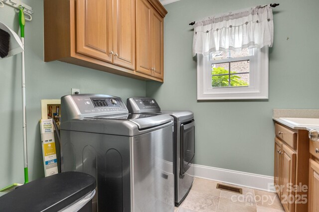 washroom featuring washer and dryer, cabinet space, tile patterned flooring, baseboards, and visible vents