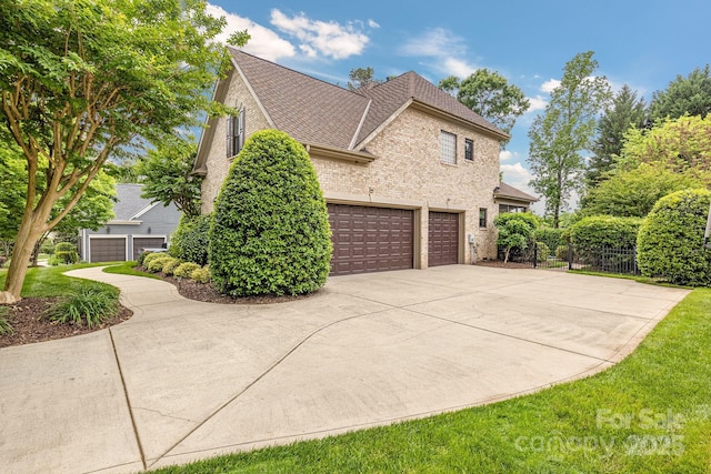 view of side of property with fence, roof with shingles, an attached garage, brick siding, and driveway