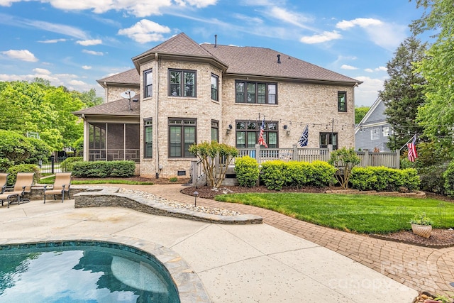 back of property with a sunroom, a shingled roof, brick siding, a patio area, and a fenced in pool