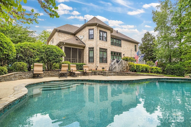 outdoor pool with a sunroom and a patio