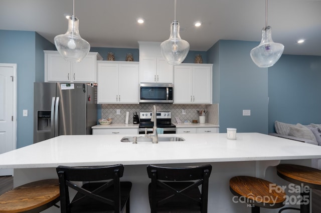 2932 Pirates Pl, Charlotte, NC 28216 - kitchen featuring appliances with stainless steel finishes, a breakfast bar area, decorative backsplash, white cabinetry, and a center island with sink