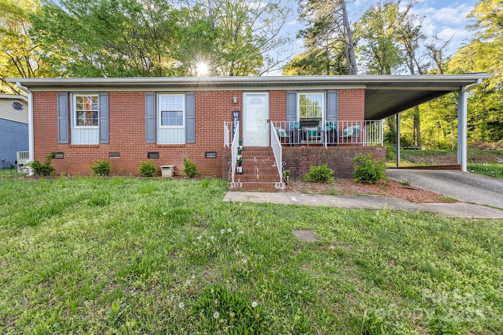 view of front of home with aphalt driveway, a carport, brick siding, and a front lawn