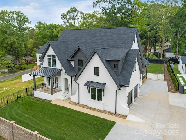 rear view of property with a yard, fence, an attached garage, a shingled roof, and concrete driveway
