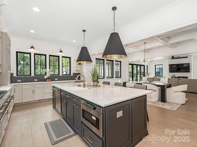 kitchen with an inviting chandelier, light wood-style flooring, recessed lighting, a kitchen island with sink, and a sink