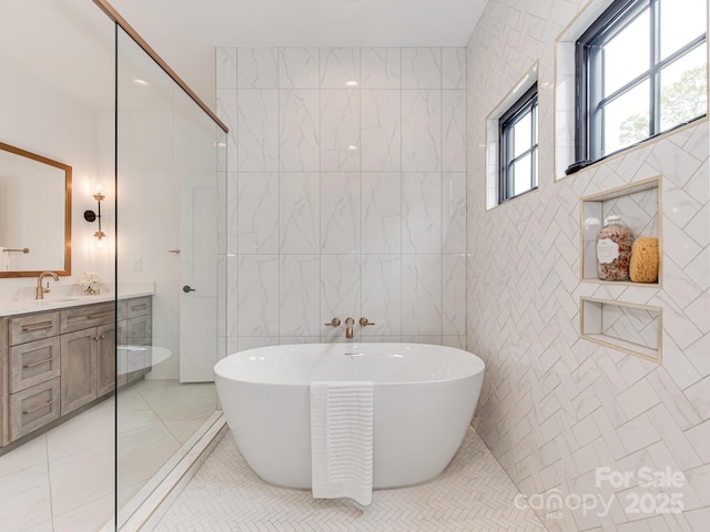 bathroom with a freestanding tub, tile walls, a walk in shower, vanity, and marble finish floor