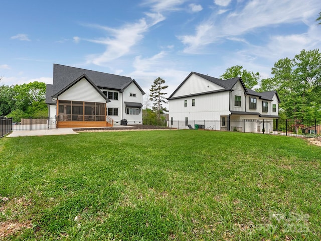 back of property featuring a fenced backyard, a sunroom, and a lawn