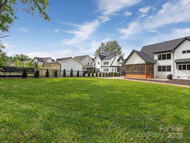 view of yard with a residential view, fence, and a sunroom