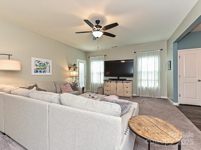 living room with a wealth of natural light, visible vents, baseboards, and a ceiling fan