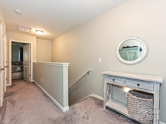 corridor with visible vents, carpet flooring, baseboards, and an upstairs landing