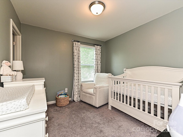 carpeted bedroom featuring a crib and baseboards