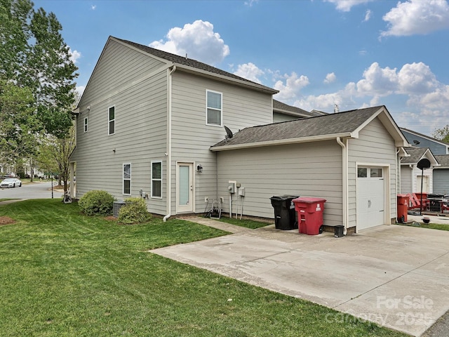 rear view of house featuring roof with shingles, a garage, a lawn, and concrete driveway
