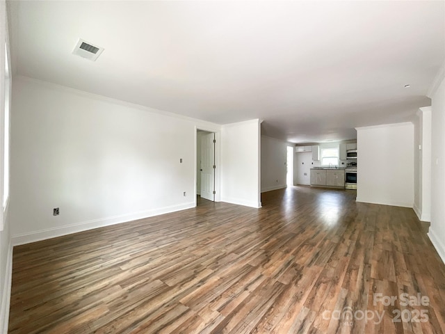 unfurnished living room featuring ornamental molding, baseboards, dark wood finished floors, and visible vents