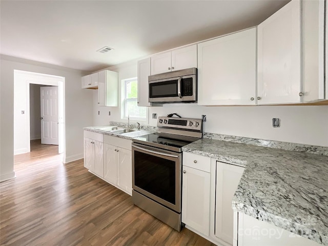 kitchen with white cabinetry, visible vents, wood finished floors, a sink, and stainless steel appliances