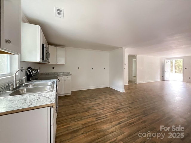 kitchen featuring visible vents, white cabinets, a sink, open floor plan, and stainless steel microwave
