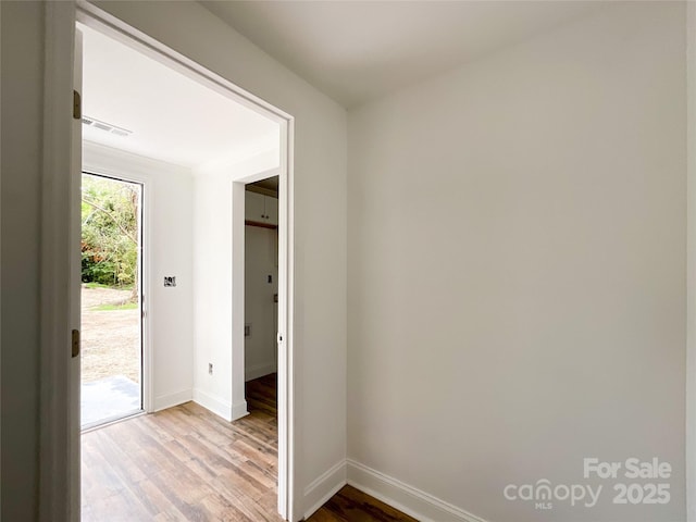 unfurnished room featuring visible vents, baseboards, and wood finished floors