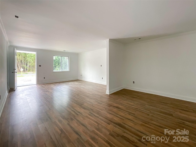 empty room featuring ornamental molding, baseboards, and dark wood finished floors