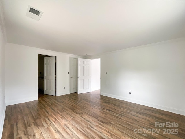 spare room featuring visible vents, baseboards, and wood finished floors