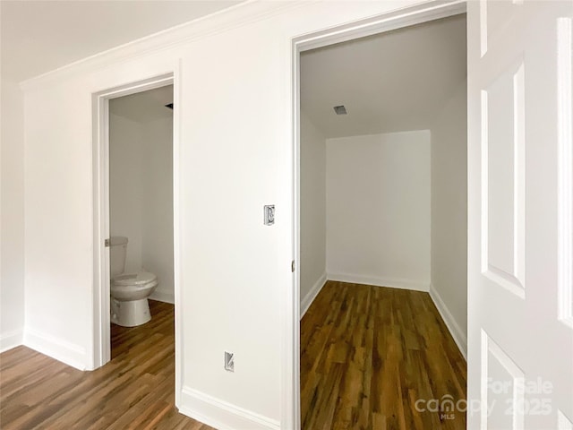 corridor featuring wood finished floors, baseboards, and visible vents