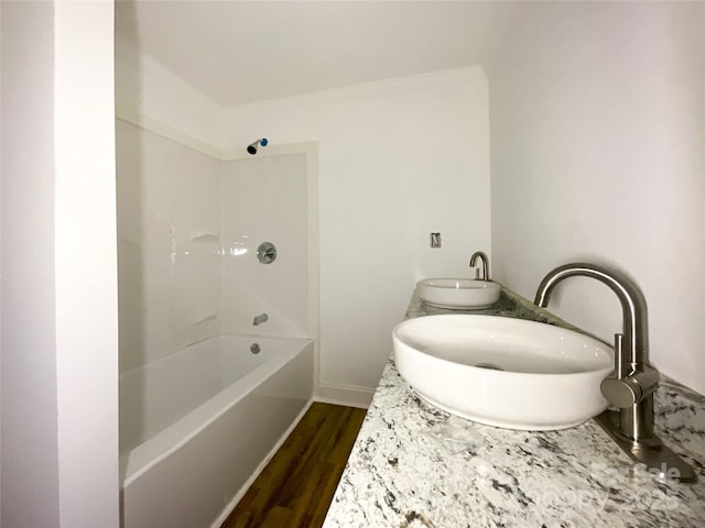 bathroom with wood finished floors, a sink, bathtub / shower combination, and baseboards