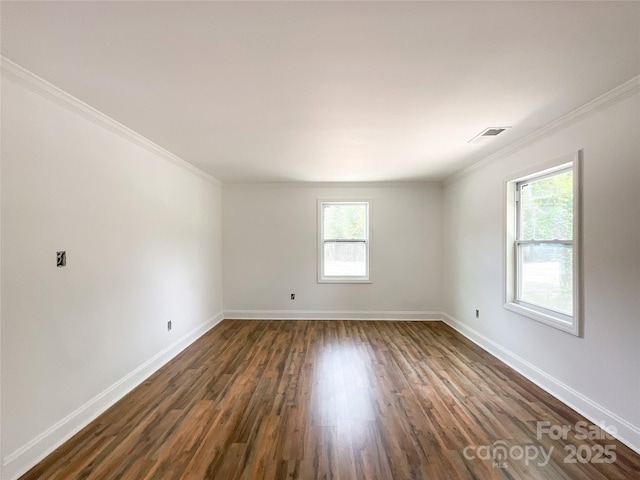 spare room featuring dark wood-type flooring, ornamental molding, baseboards, and visible vents