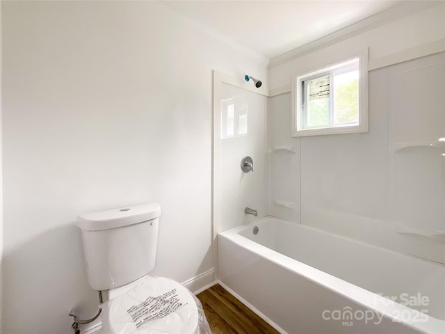 full bath with crown molding, bathing tub / shower combination, toilet, wood finished floors, and baseboards