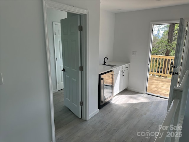 1413 Hateras Ave, Charlotte, NC 28216 - hallway with wine cooler, baseboards, light wood-style flooring, and a sink