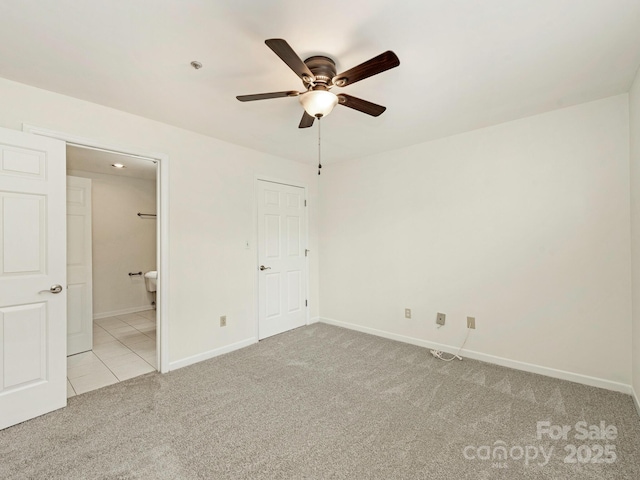 unfurnished bedroom featuring light carpet, baseboards, connected bathroom, and ceiling fan