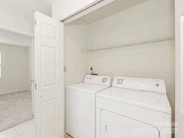 clothes washing area featuring light tile patterned floors, washing machine and clothes dryer, light colored carpet, and laundry area