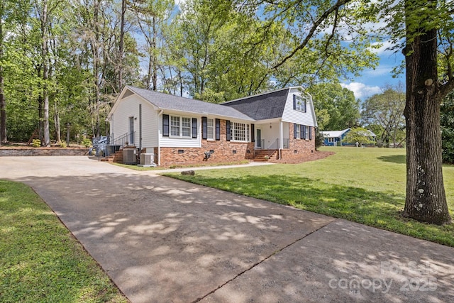 view of front of house featuring a shingled roof, concrete driveway, brick siding, a front lawn, and a gambrel roof