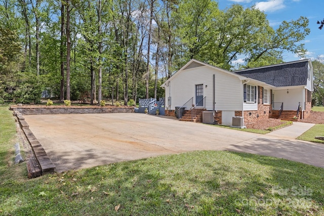 view of side of property featuring a yard, roof with shingles, and central AC