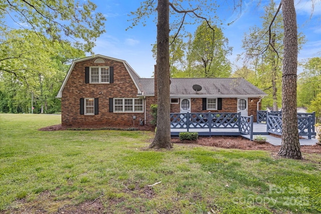 view of front of property with a wooden deck, a front lawn, and brick siding