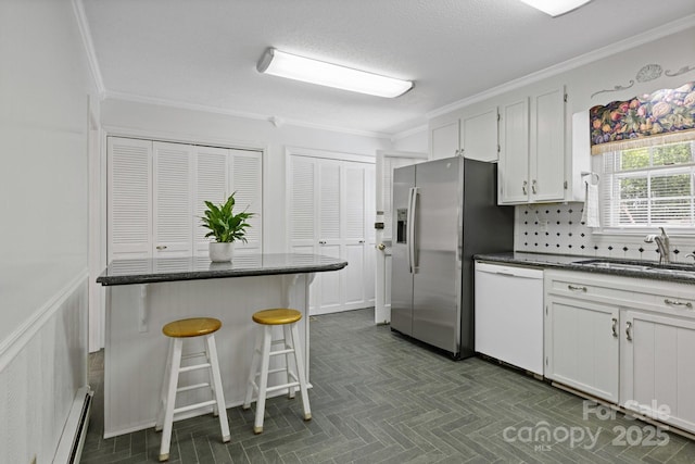 kitchen featuring stainless steel refrigerator with ice dispenser, dishwasher, a sink, baseboard heating, and crown molding