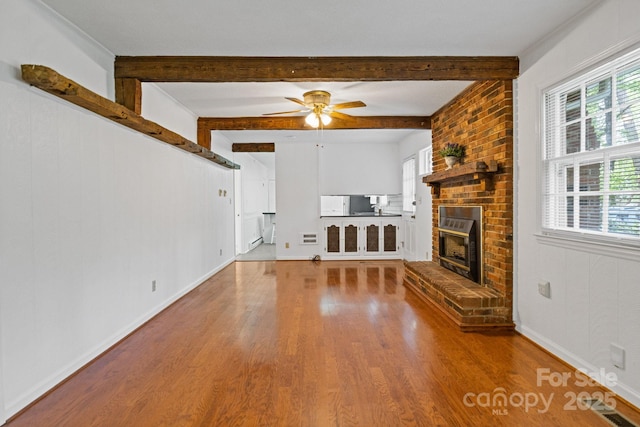 unfurnished living room with a ceiling fan, wood finished floors, and a healthy amount of sunlight