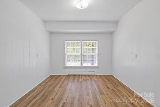 unfurnished room featuring baseboard heating, ornamental molding, and wood finished floors