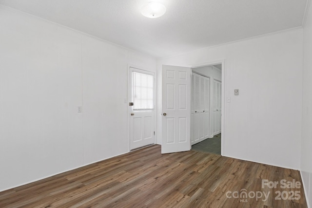 unfurnished room with crown molding and wood finished floors