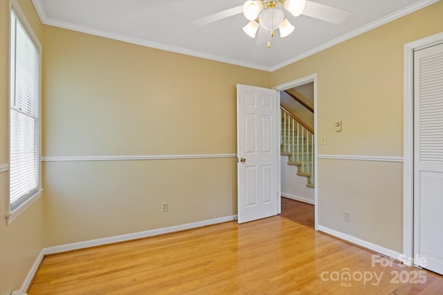 interior space with baseboards, a ceiling fan, crown molding, and wood finished floors
