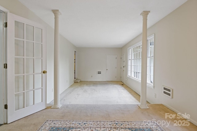 carpeted empty room featuring heating unit and ornate columns