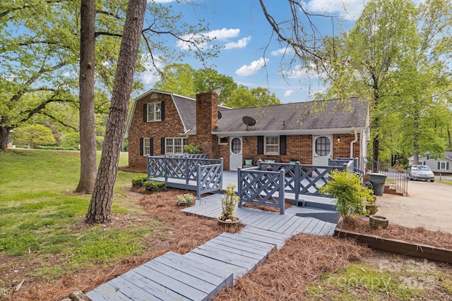 view of front facade with brick siding, a wooden deck, a chimney, and a front lawn