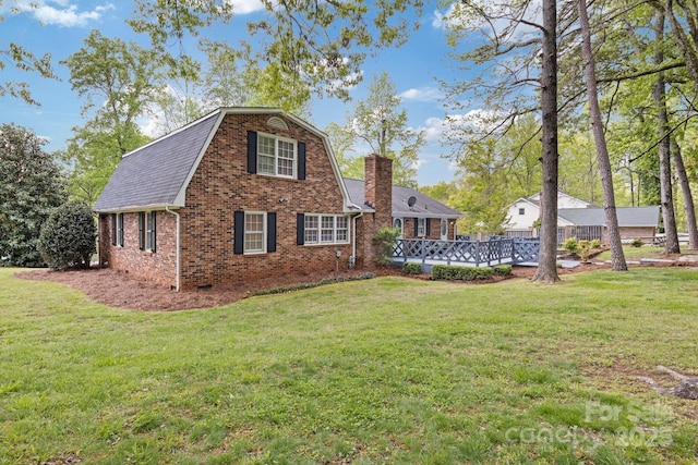 exterior space featuring a chimney, brick siding, a yard, and roof with shingles
